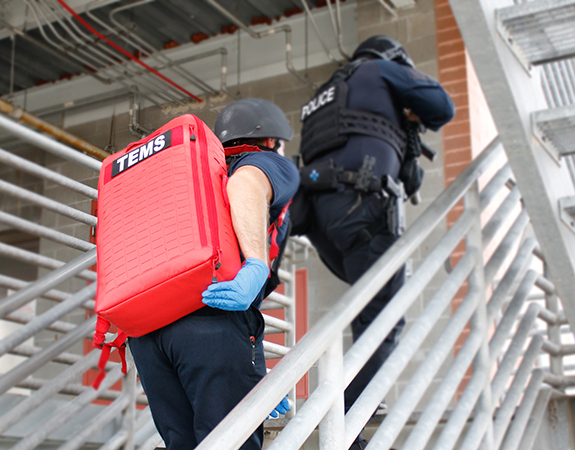 Two uniformed ems walking up stairs with medical supplies