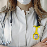 A silicone nurse watch in bright yellow is displayed on a white lab coat, alongside a stethoscope.