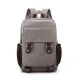 A grey canvas sling backpack with adjustable straps, side mesh pockets, and a front pocket. It features branding.
