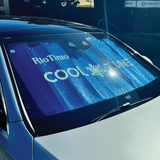 A foldable car sunshade in blue with branding, placed on the windshield of a silver car.