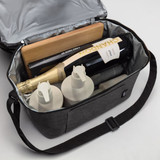 A grey cooler bag containing bottles of wine, skincare products, and a wooden board, all neatly organised inside.