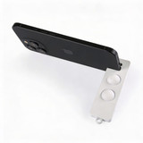 A white phone stand supports a black smartphone, featuring two circular grips for stability.