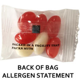 A plastic bag containing mini jelly beans, featuring red and white sweets. The bag has a logo and allergen statement.
