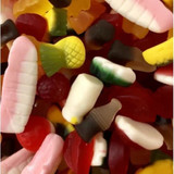 A mix of colourful lollies, including gummy shapes of ice creams, fruits, and cones, clustered together.