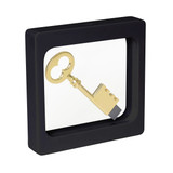 A gold key displayed inside a square black floating box with a clear front. The box includes a logo on the side.