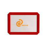 A silicone baking mat with a red border and a logo in the centre. The mat is predominantly grey.