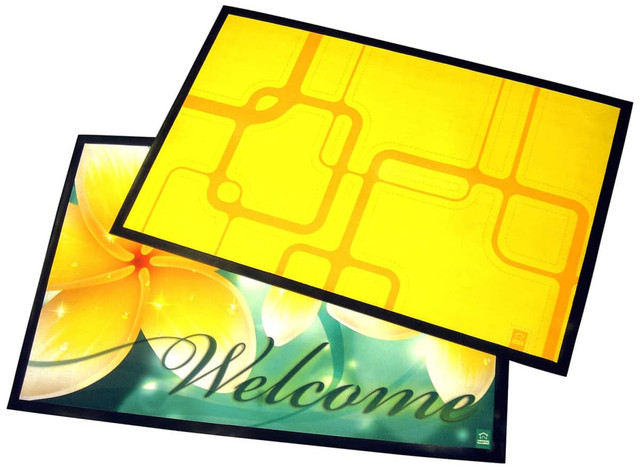 A large table mat featuring a vibrant yellow design on one side and a floral green "Welcome" design on the other.