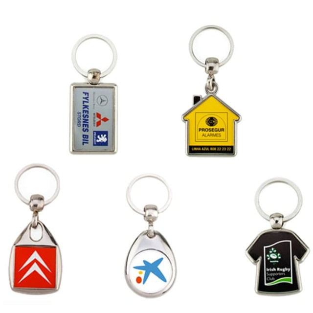 A collection of five metal key rings in various shapes and colours, each featuring a different logo or design.