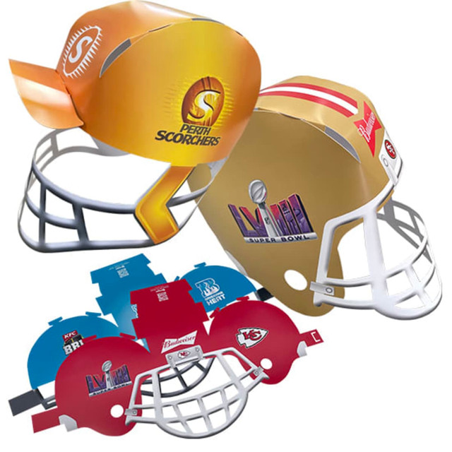 A collection of colourful novelty paper helmets, including designs in orange, gold, and red, featuring various logos.