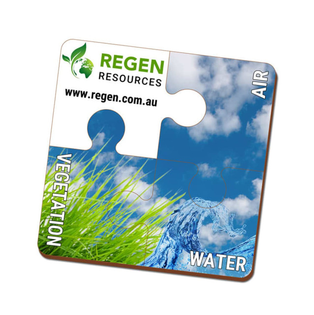 A square eco-friendly MDF coaster featuring puzzle piece design in blue, green, and white, with a logo.