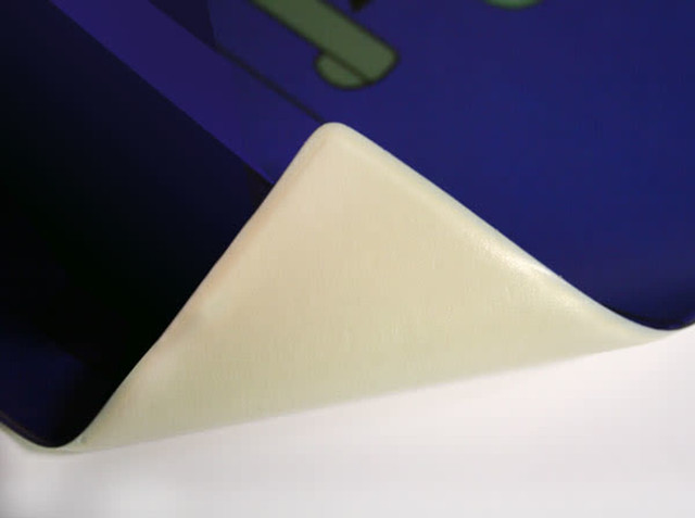 A purple mouse mat with a textured surface, featuring a white, rolled edge. It has a logo visible in the design.