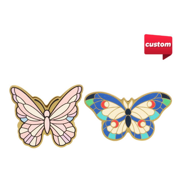 Two vibrant metal butterfly clips, one in pink and gold, the other in blue and cream, featuring a logo.