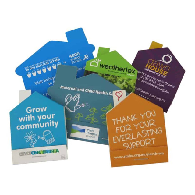 A collection of colourful seed packets shaped like houses, featuring various logos and designs related to community and support.