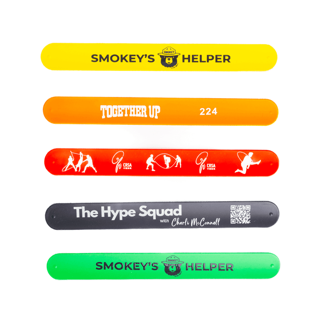 Five silicone slap-bands in yellow, orange, red, and green featuring various designs and a logo on each.