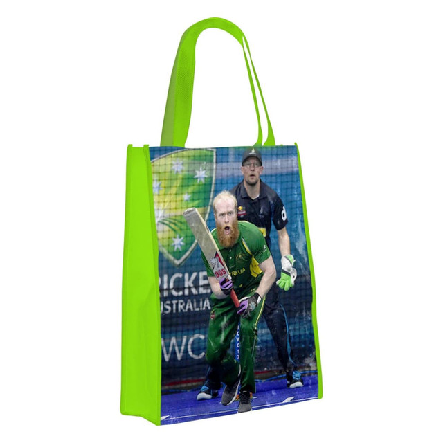 A green tote bag featuring a cricket player in action, with a logo design on one side.