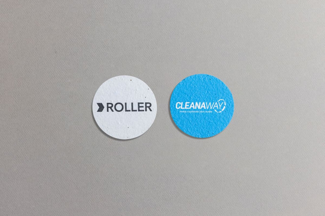Two circular seed paper pieces, one white with "ROLLER" text and one blue featuring the "CLEANAWAY" logo.