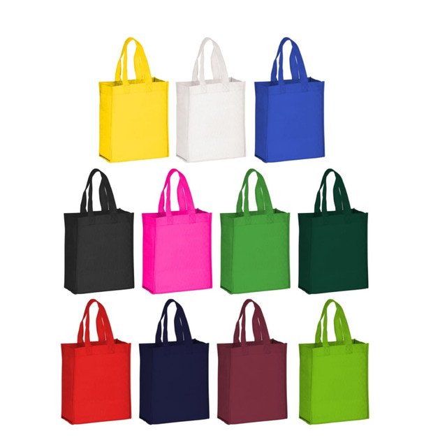 A collection of non-woven tote bags in various colours, including yellow, white, black, pink, green, navy, and burgundy.