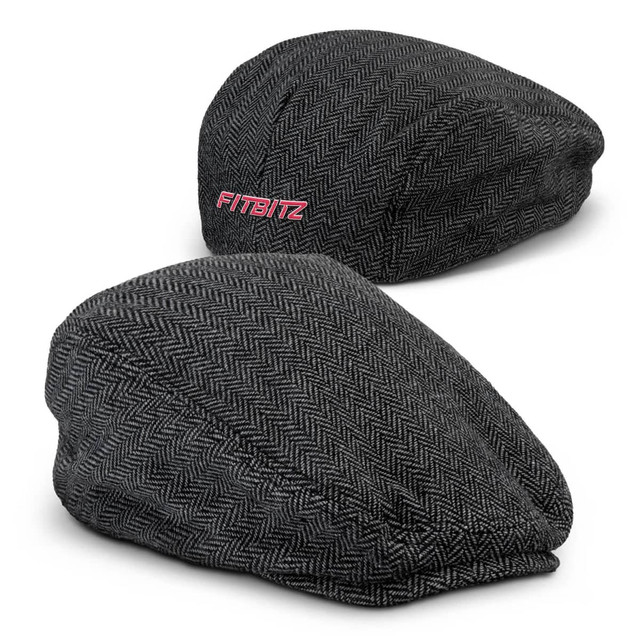 A tweed flat cap in grey herringbone pattern with a branding logo on the side.