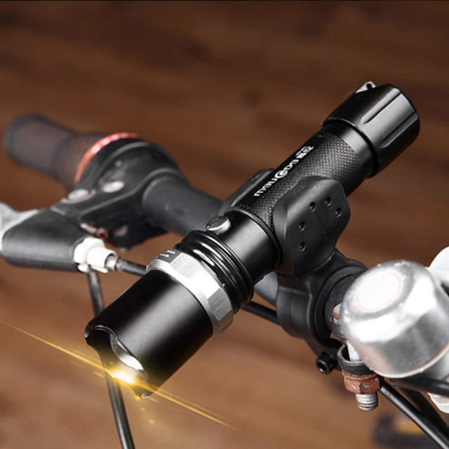 A sleek black torch mounted on a bicycle handlebar, featuring a sturdy design and a bright light beam.