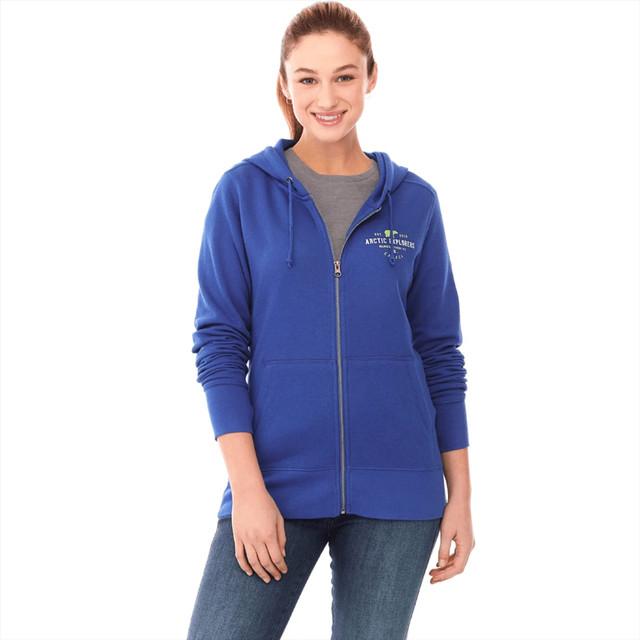 A woman wearing a blue fleece zip hoody with a logo, paired with a grey top and jeans.