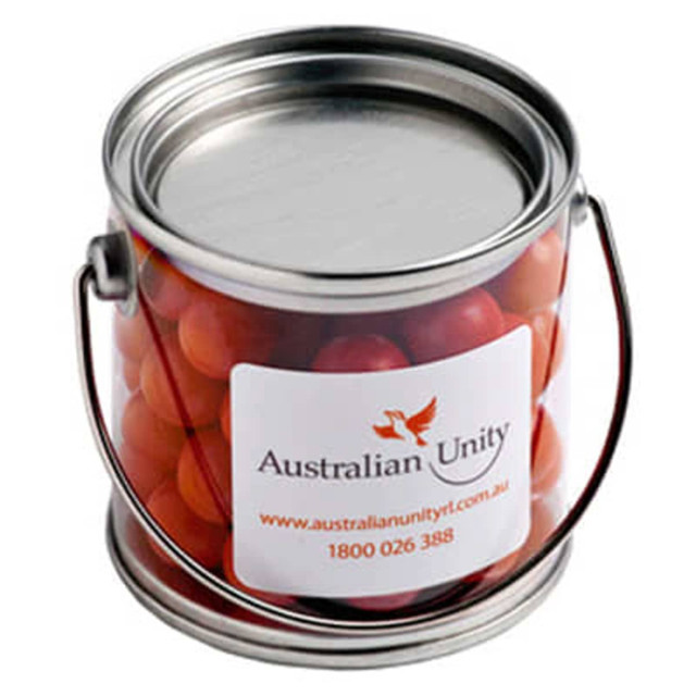 A small PVC bucket filled with orange choc drops, featuring a metal handle and a branding label.