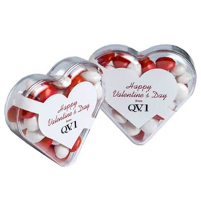 Acrylic heart-shaped container filled with red and white chewy fruits, featuring a logo and festive branding.