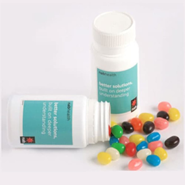 A pill jar filled with colourful jelly beans in various shades, alongside an open jar with beans spilling out.