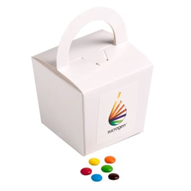 A coloured noodle box containing M&Ms in various colours, placed alongside colourful chocolate beans.