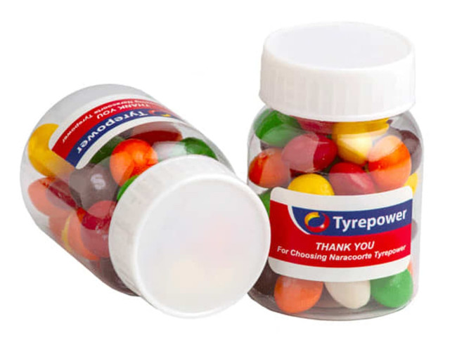 A clear jar filled with colourful Skittles candies, featuring a logo on the lid.