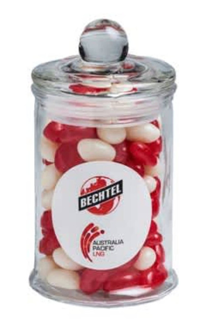 A small glass apothecary jar filled with red and white jelly beans, featuring a logo on the front.