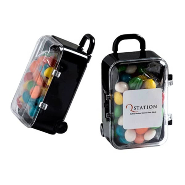 A small black carry-on case filled with colourful chewy fruit candies, featuring a clear lid and a logo.