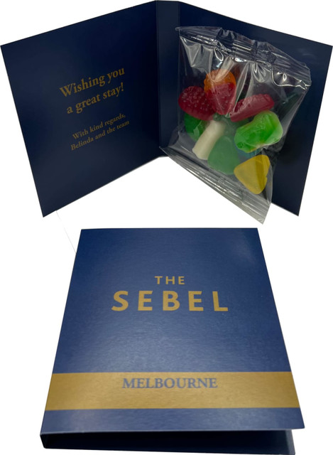 A gift card with a blue cover opens to reveal a bag of mixed lollies in various colours, including red, green, and yellow.