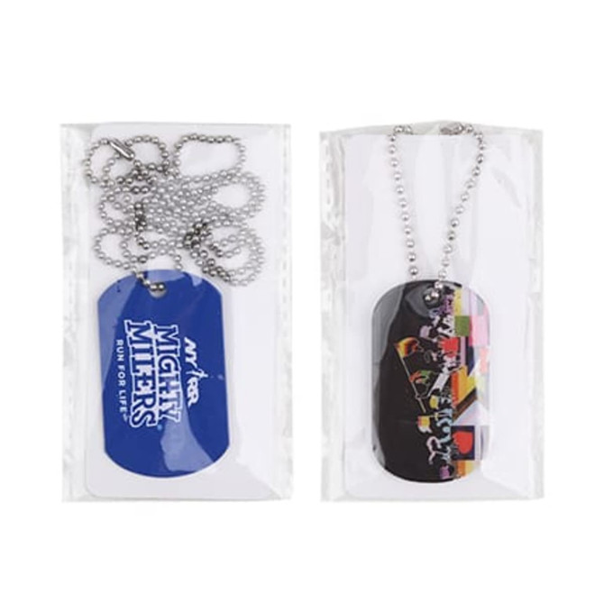 Two dog tags in packaging, one blue with a logo and the other multi-coloured featuring a graphic design. Both come with chains.