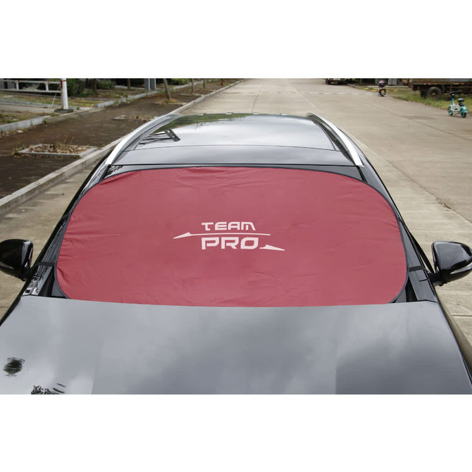 A red car shade covers the windshield of a parked vehicle, featuring a logo in the centre.