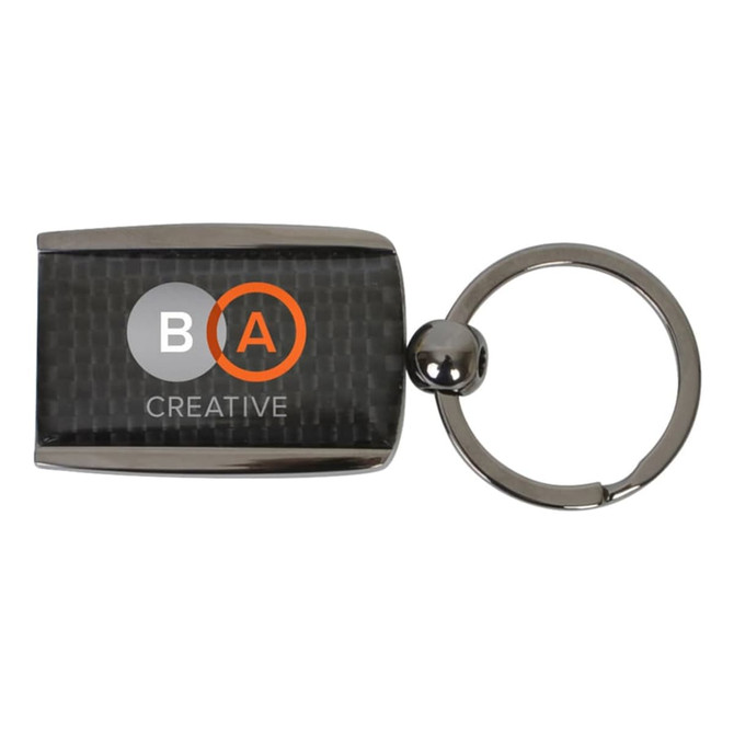 A carbon fibre keychain featuring a rectangular design and a metallic silver ring. It includes a logo.