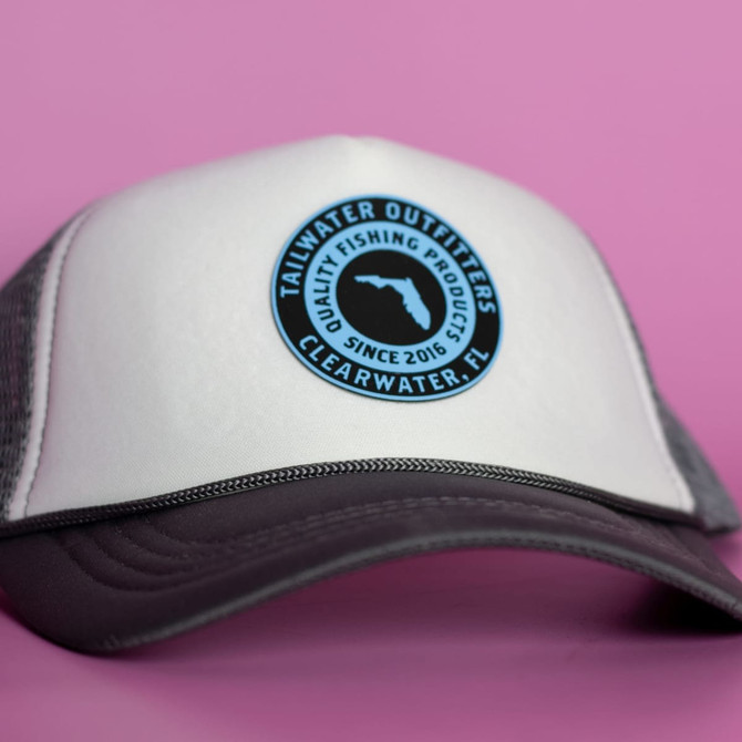 A cap featuring a white front and grey mesh back, with a circular logo at the front.