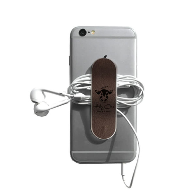 A smartphone with a brown leather strap holding wrapped earphones, featuring a logo. The phone is silver in colour.