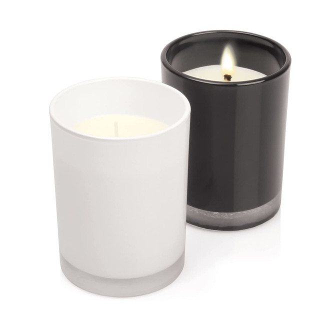 Two glass candles, one white and one black, featuring a minimalist design and a silver base.