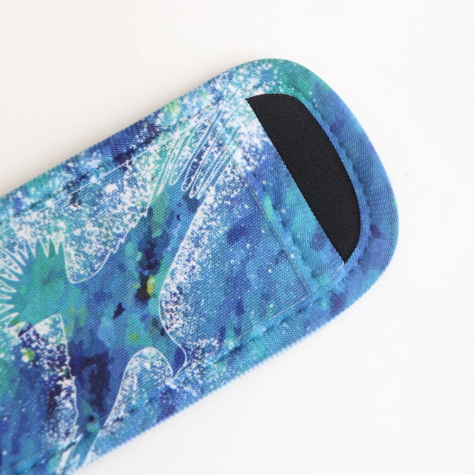 An Icy Pole Holder in vibrant blue and green patterns, featuring a soft fabric surface and a black opening.