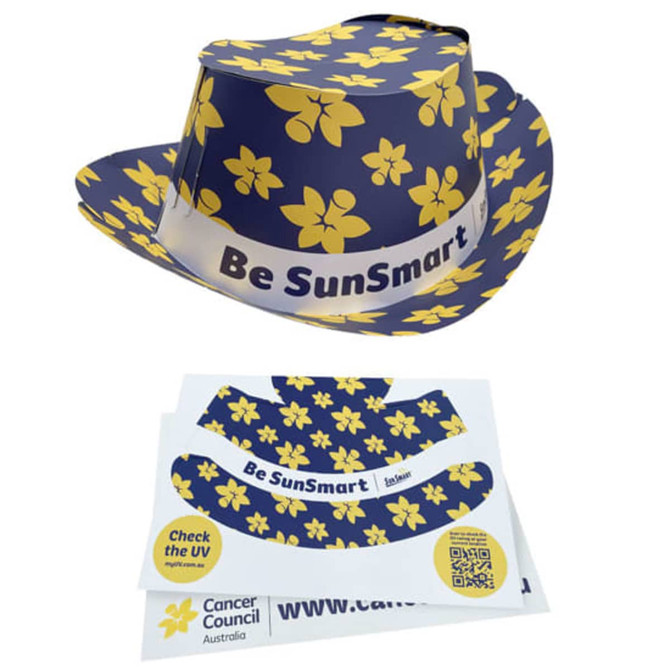 A navy sun hat with yellow floral patterns and a logo, accompanied by a printed design template.
