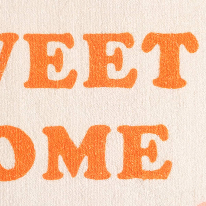 A textured mat featuring large, bold orange lettering against a cream background with a logo.