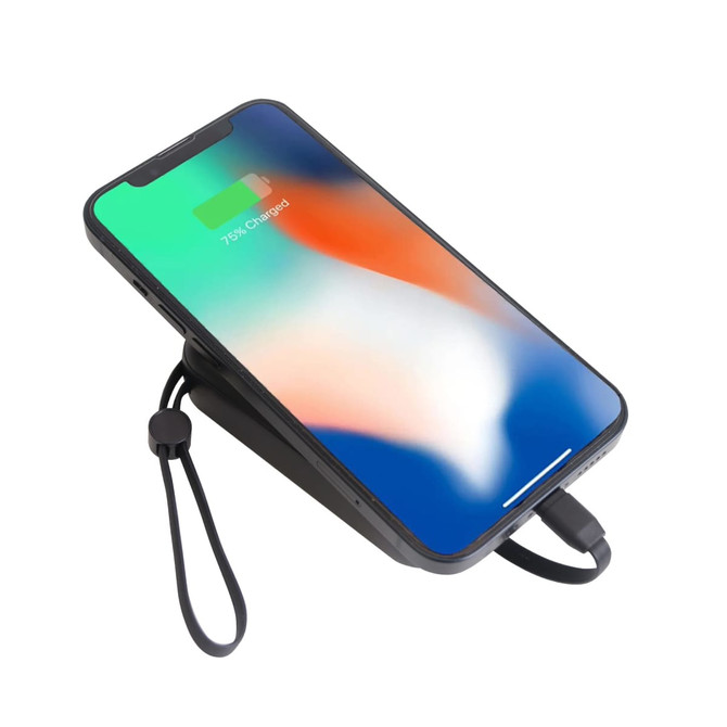 A black portable power bank with a phone charging on top, showing a green and orange screen.