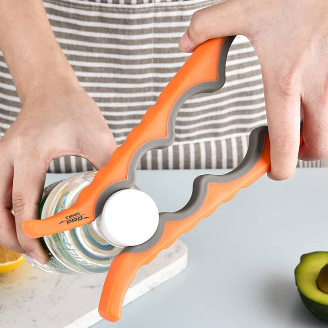 A drink bottle is being opened using a multi-purpose jar opener in orange and grey, featuring a grip design.