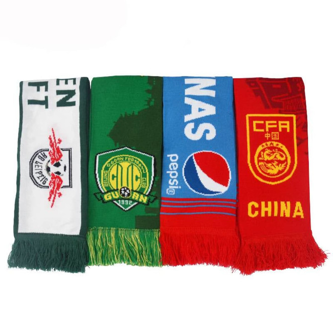 Four custom knitted scarves in green, red, and blue, featuring various designs and a logo on one.