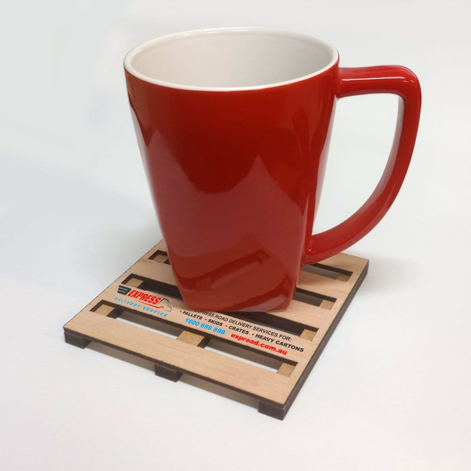 A red mug rests on a brown eco MDF pallet coaster. The coaster has a logo and a wooden texture.