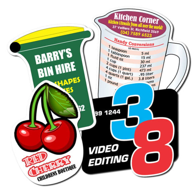 Custom-shaped fridge magnets in various colours, featuring a cherry, measuring jug, and business card designs, with logos.