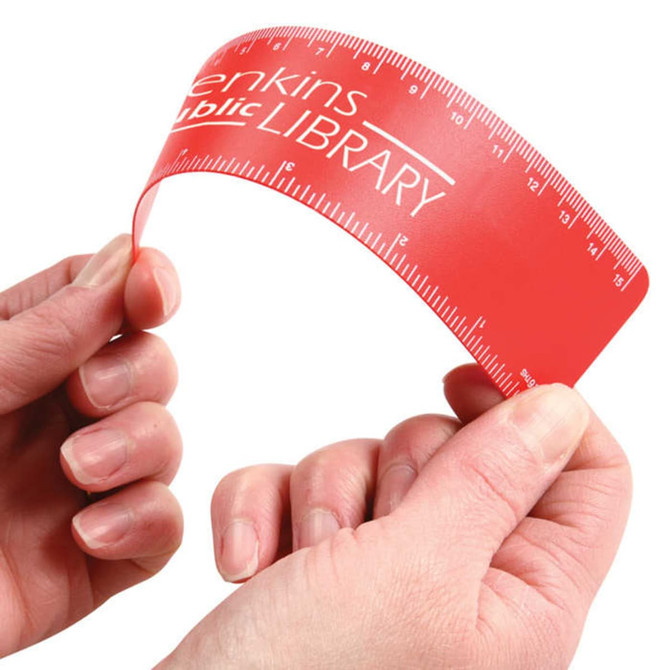 A flexible red ruler held between two hands, featuring measurements and a logo.