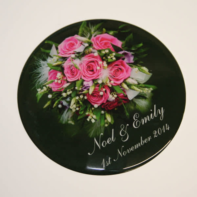 A round coaster featuring a bouquet of pink roses with green accents, adorned with text and a logo.