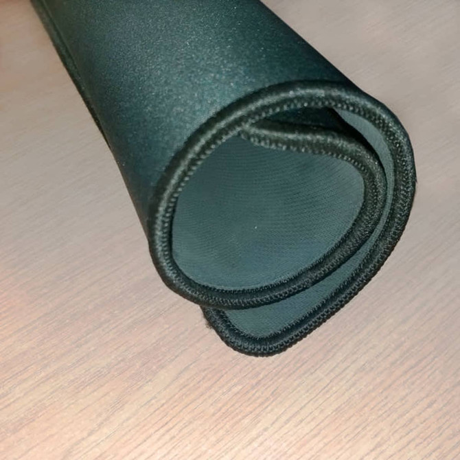 A black deluxe overlocked fabric mousepad, rolled up, showing the textured surface and stitched edges.