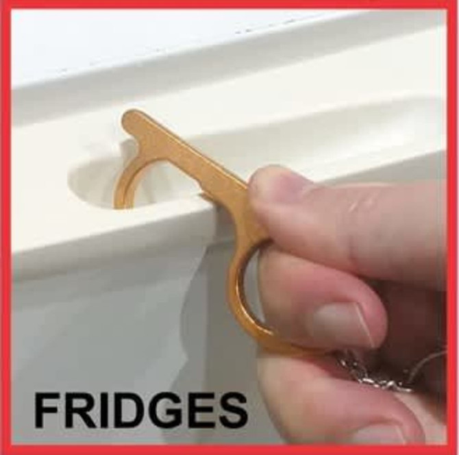 A copper-coloured No-Touch Door Opener is being used to open a fridge door.